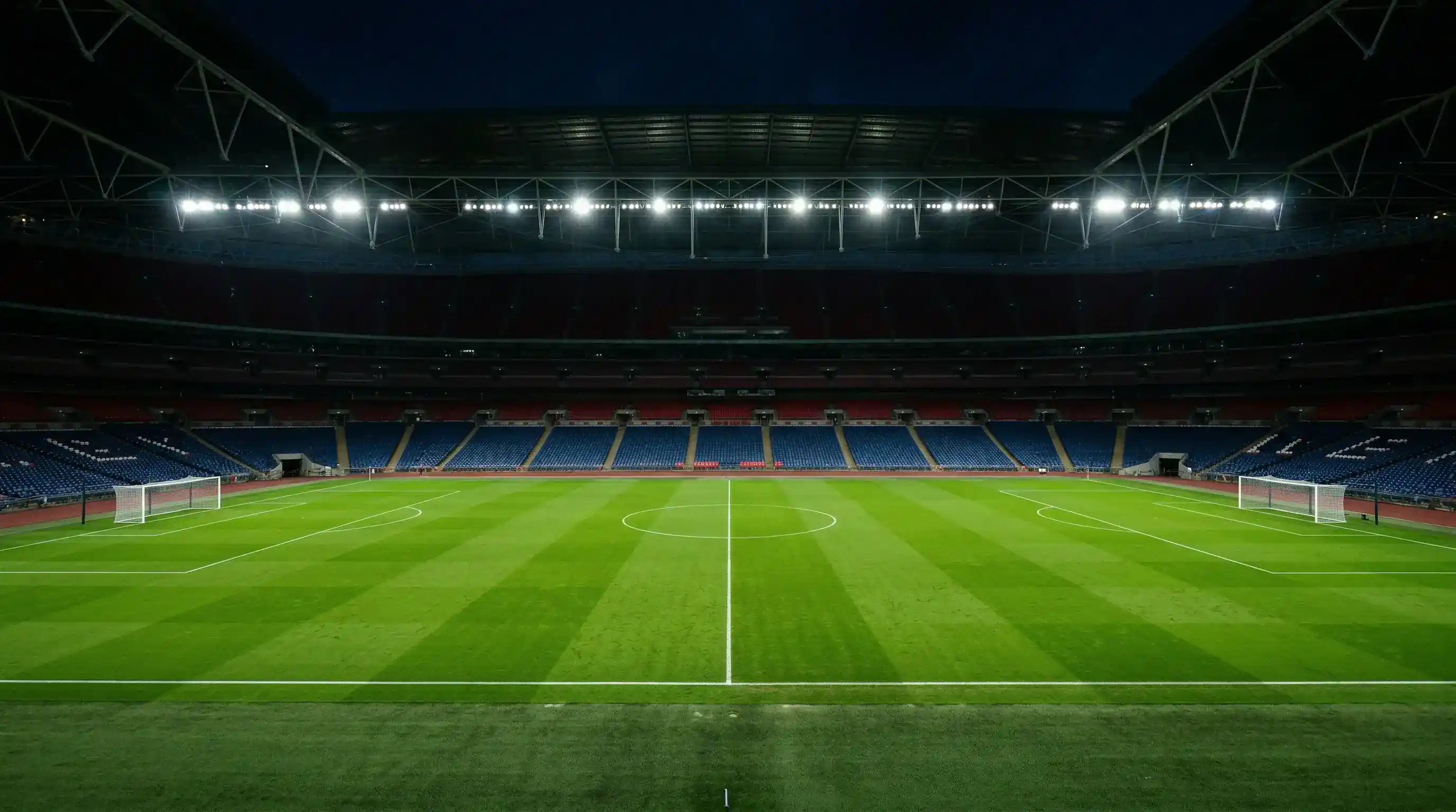 Dos porterías de fútbol enfrentadas en un campo de césped natural bajo focos de estadio